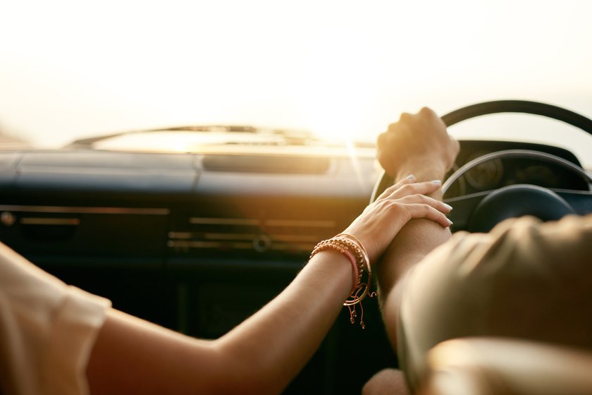 Paar im Auto, Frau legt Hand auf Arm des Mannes