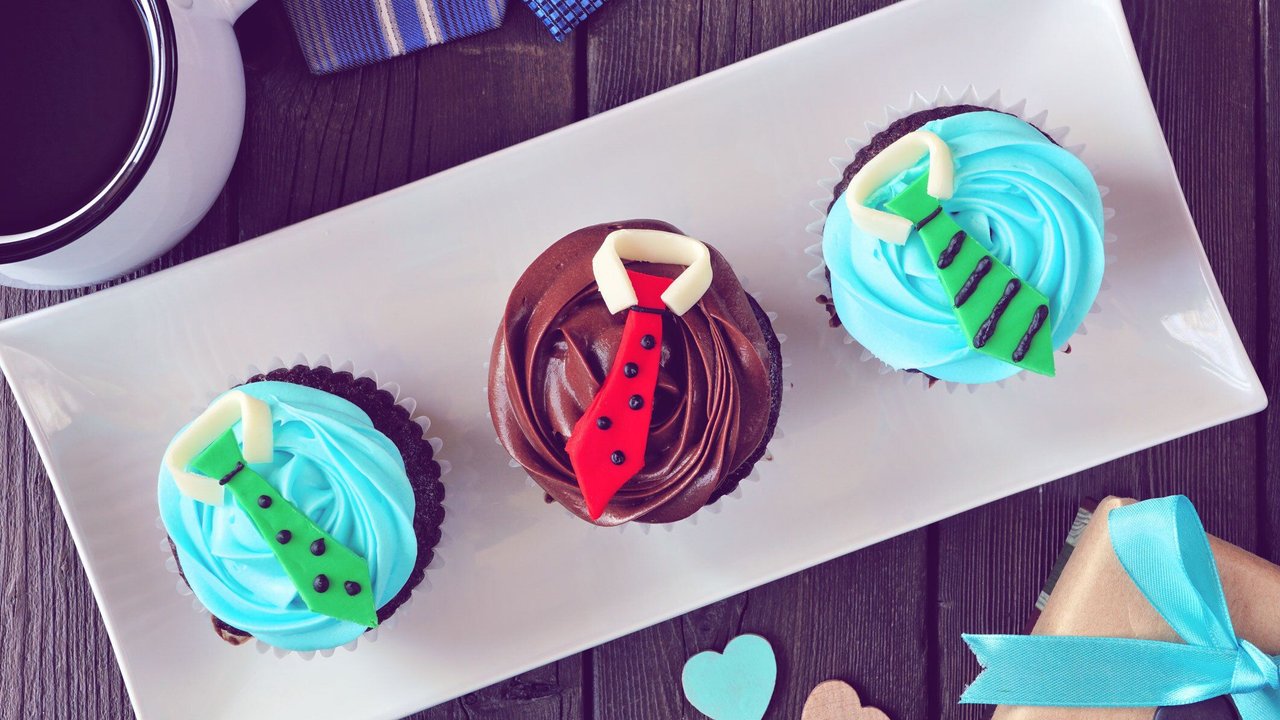 Tasty Fathers Day shirt and tie cupcakes. Overhead view table scene on a dark wood background.