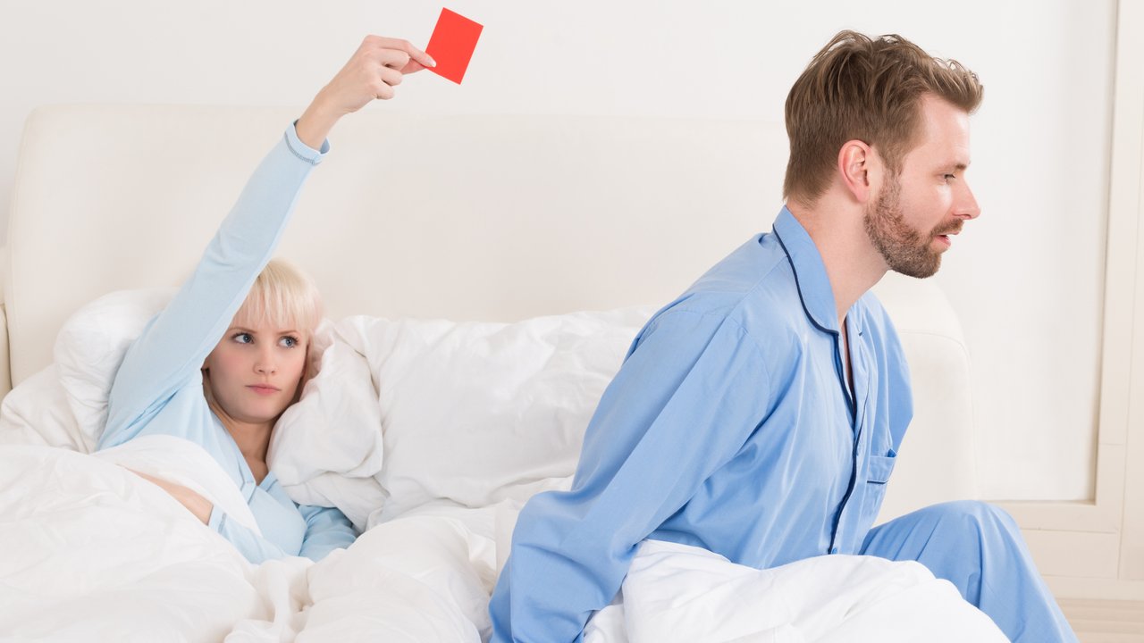 Unhappy Young Woman Showing Red Card To Man In Bed