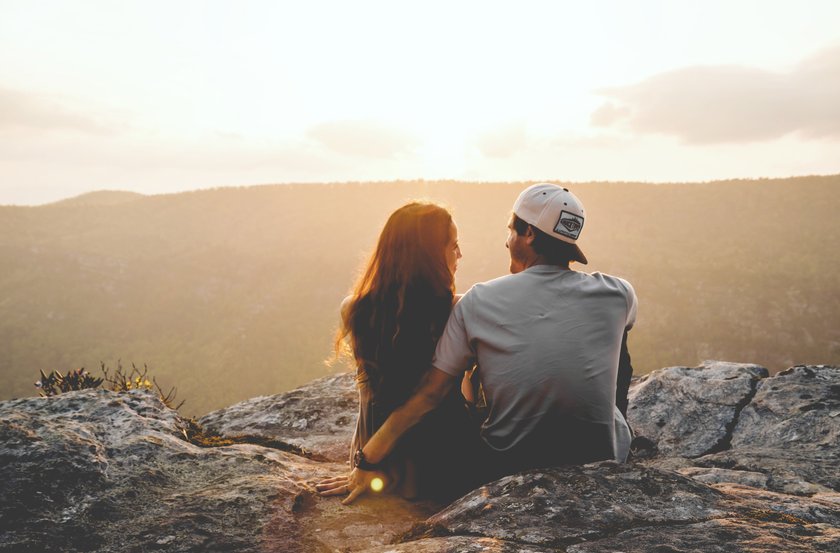 Paar sitzt bei einem Sonnenuntergang auf einem Felsen