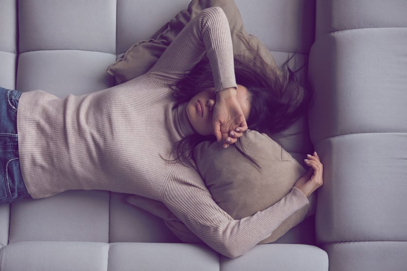erschöpfte Frau, die auf dem Sofa liegt