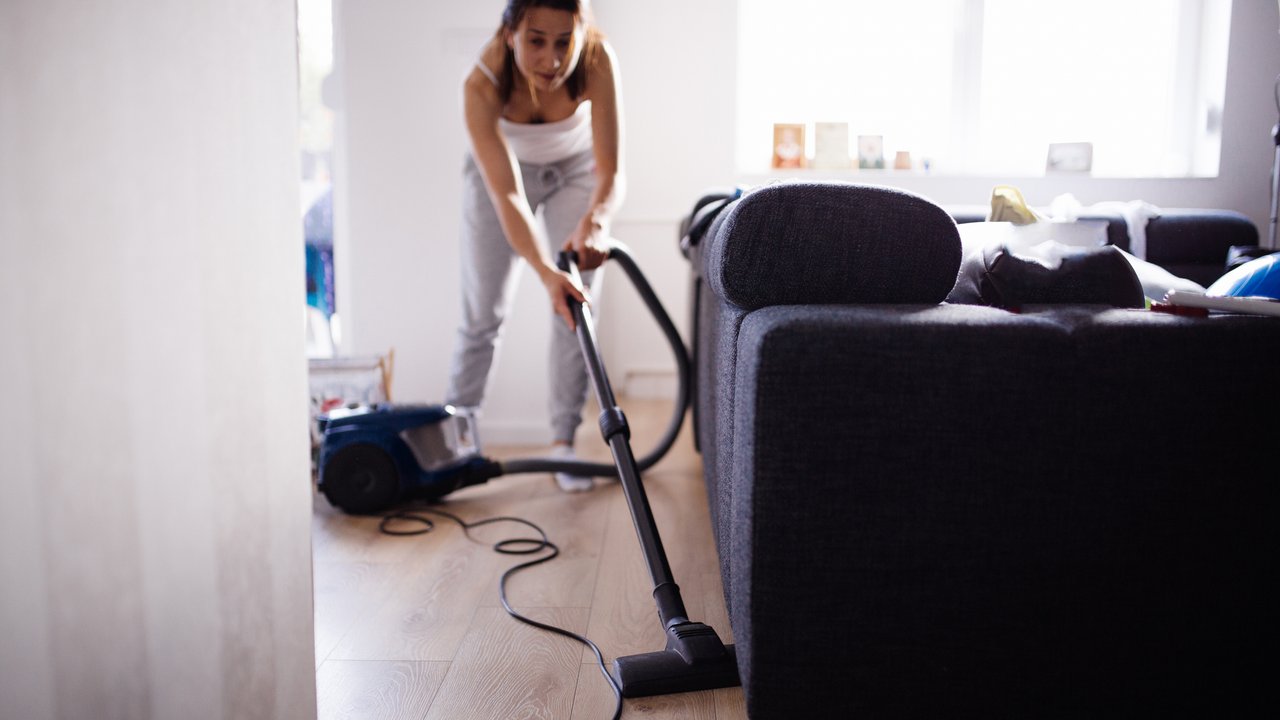 Eine Frau putzt im Wohnzimmer und staubsaugt