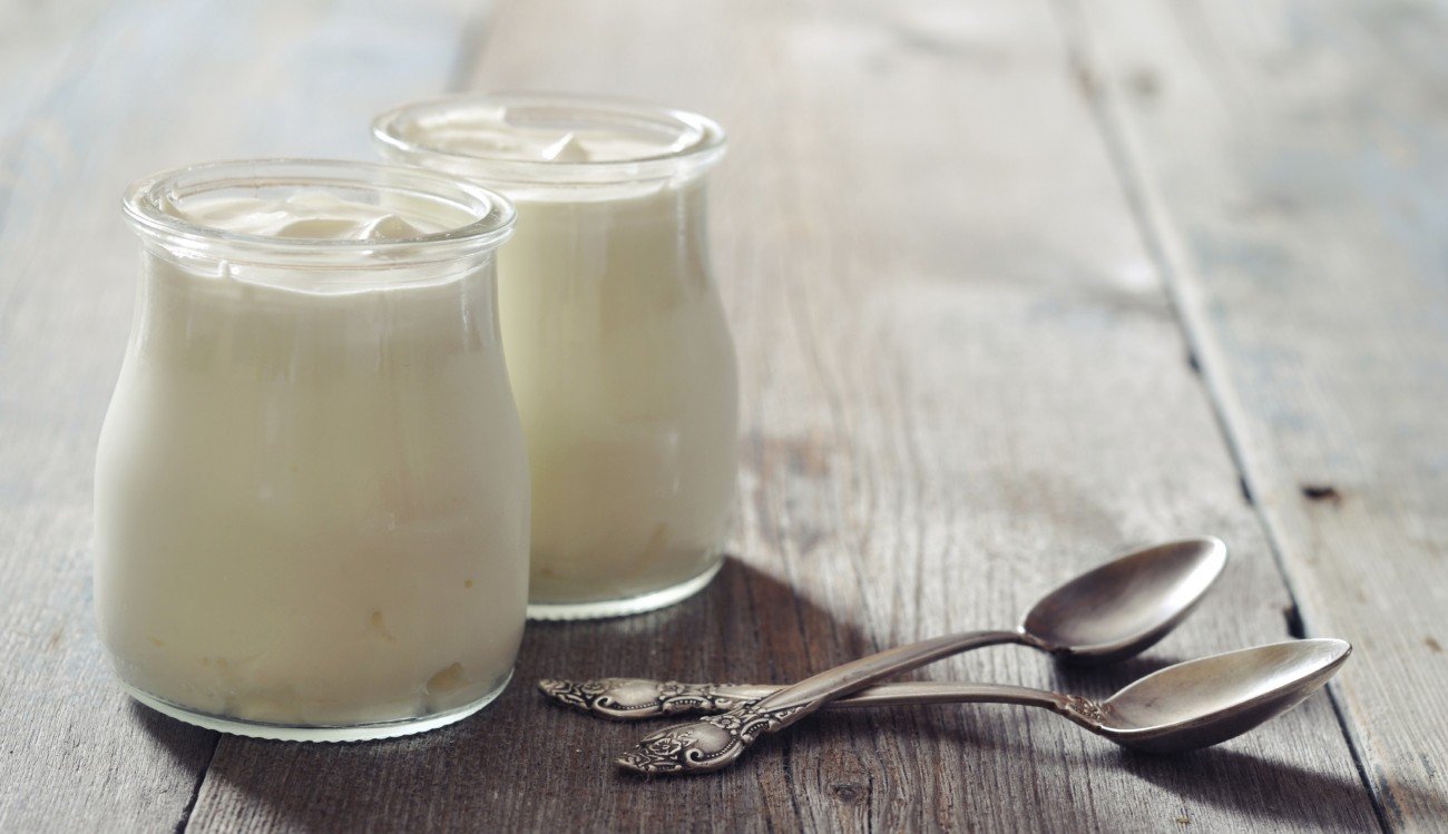 Greek yogurt in a glass jars with spoons on wooden background Greek yogurt in a glass jars with spoons on wooden background