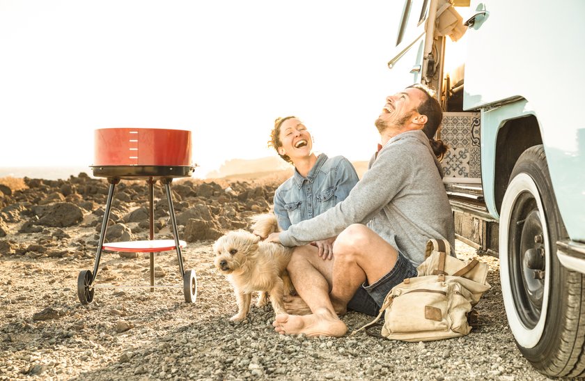 Paar sitzt mit Hung vor einem Campingbus und lacht