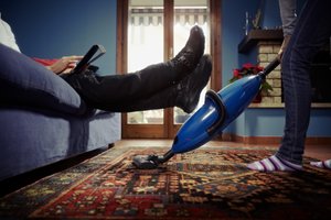 Frauen putzt, Mann sitzt auf Sofa Frauen putzt, Mann sitzt auf Sofa