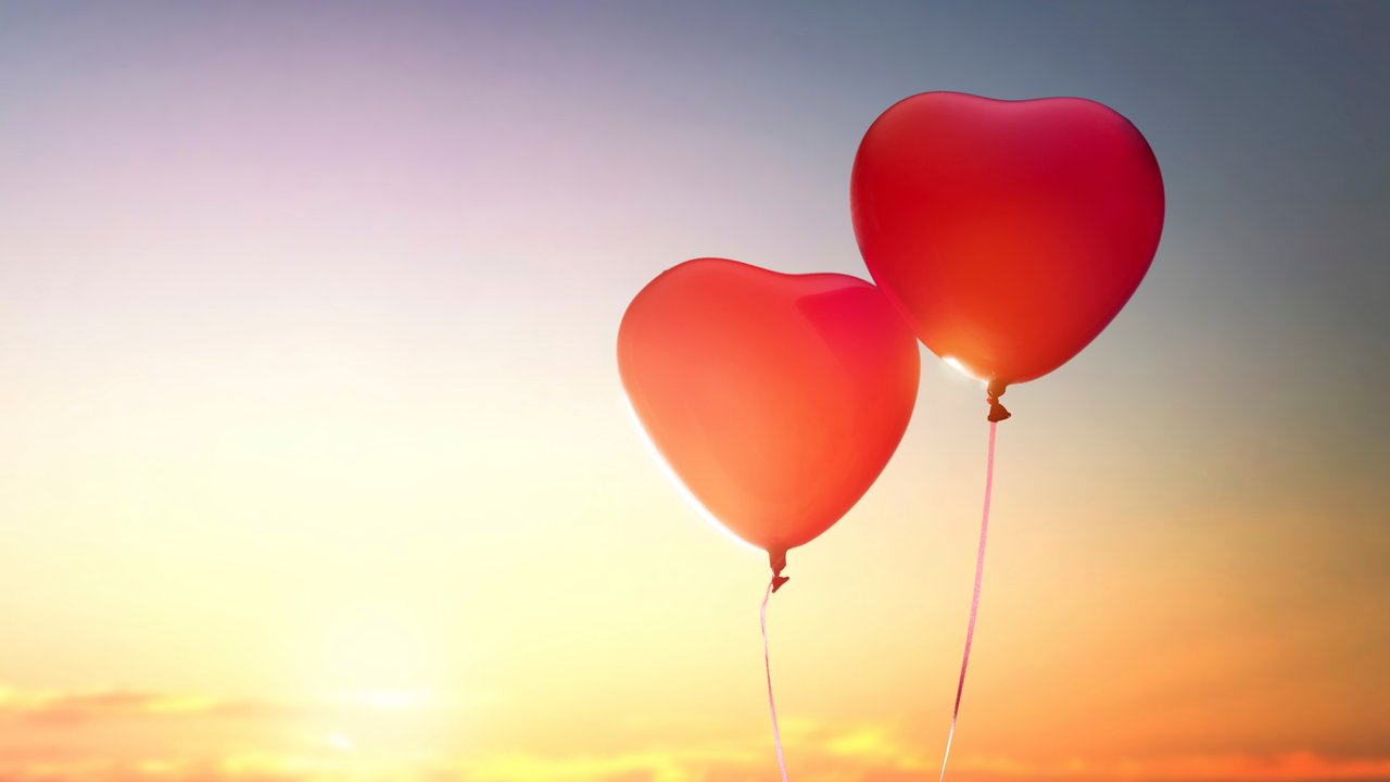 two red balloons in shape of heart on the background of sunset sky. the concept of love and Valentine's day.