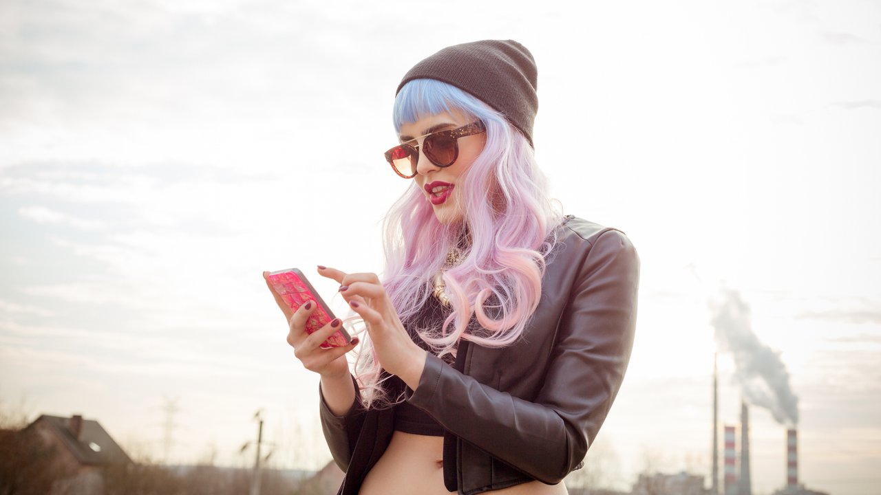 Outdoor portrait of blue-pink hair cool girl texting on phone