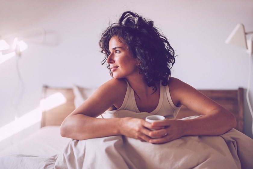 frau sitzt mit kaffee im bett