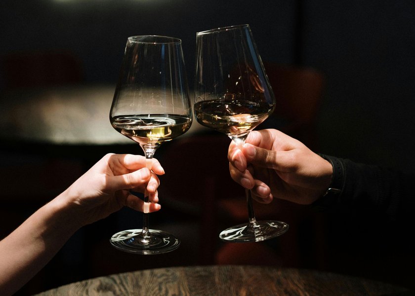 zwei Menschen stoßen mit Wein an