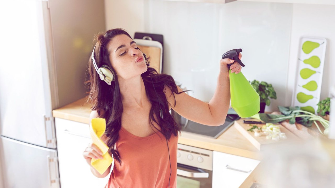 Frau gutgelaunt beim Putzen in der Küche