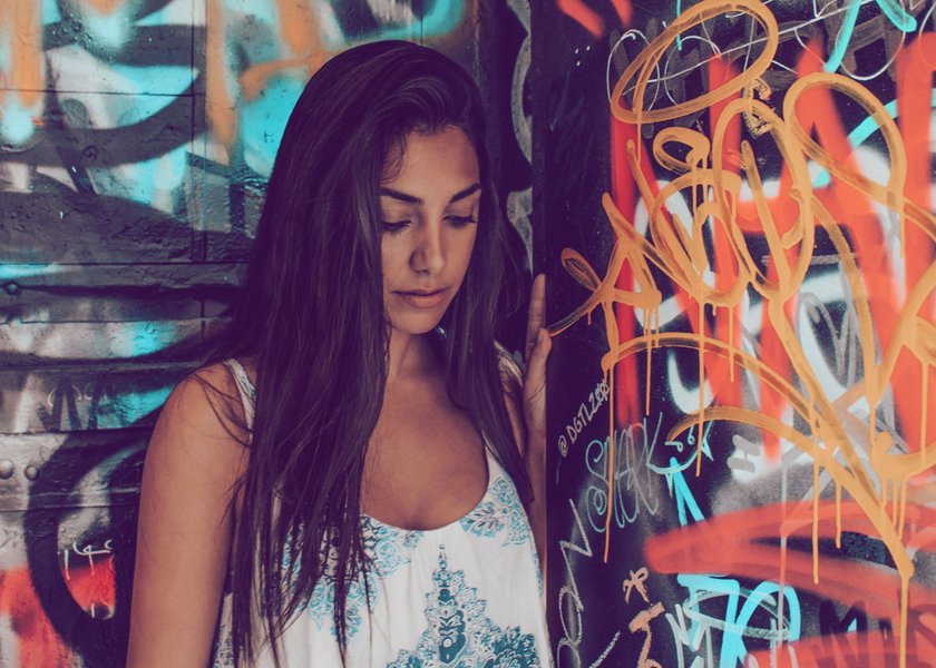 junge Frau, die vor einer Graffiti-Wand steht und nach unten schaut