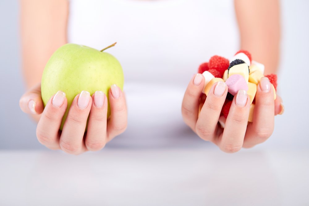 test teste ob du ausreichend vitamine zu dir nimmst desired de woman holding apple in her hand and in the other hand candies