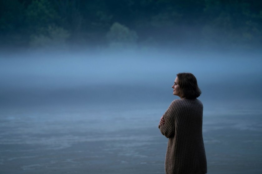 Frau im Nebel schaut auf einen Fluss