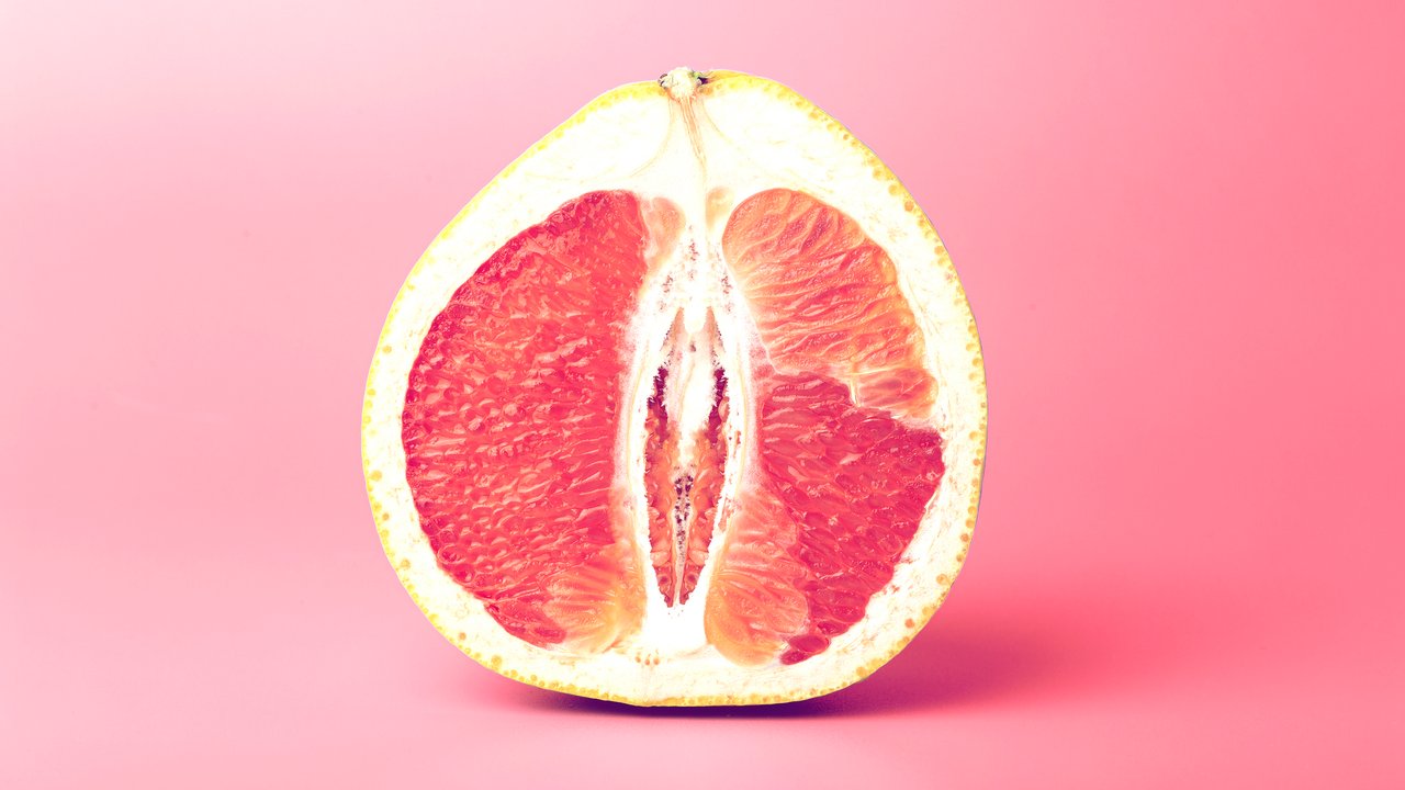 Grapefruit minimal erotic concept. Half a juicy grapefruit close up on a colored background.