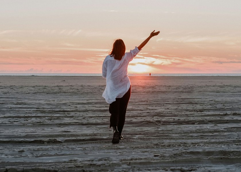 Frau, die bei Sonnenuntergang auf Meer zuspaziert