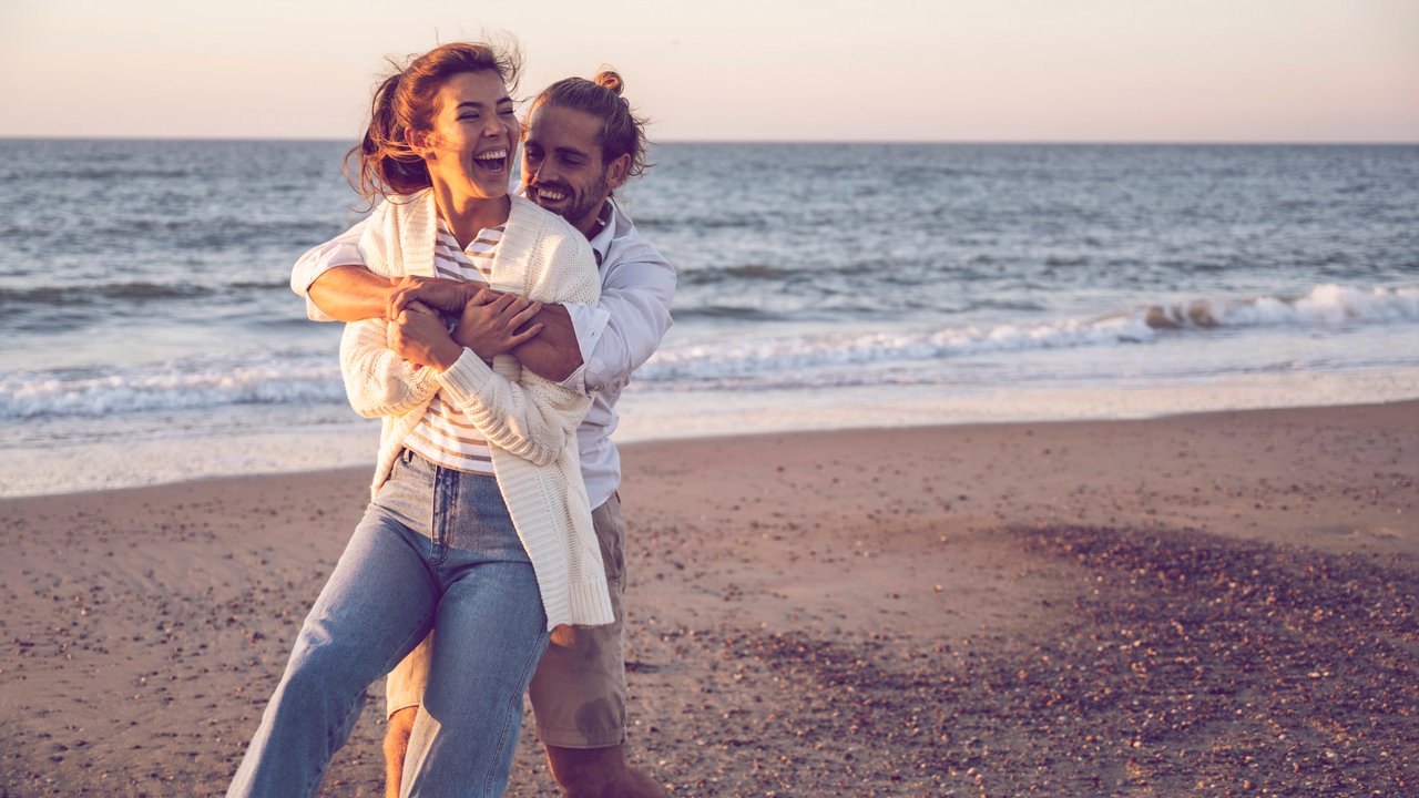 Happy young couple enjoying at beach during sunset model released Symbolfoto UUF22373