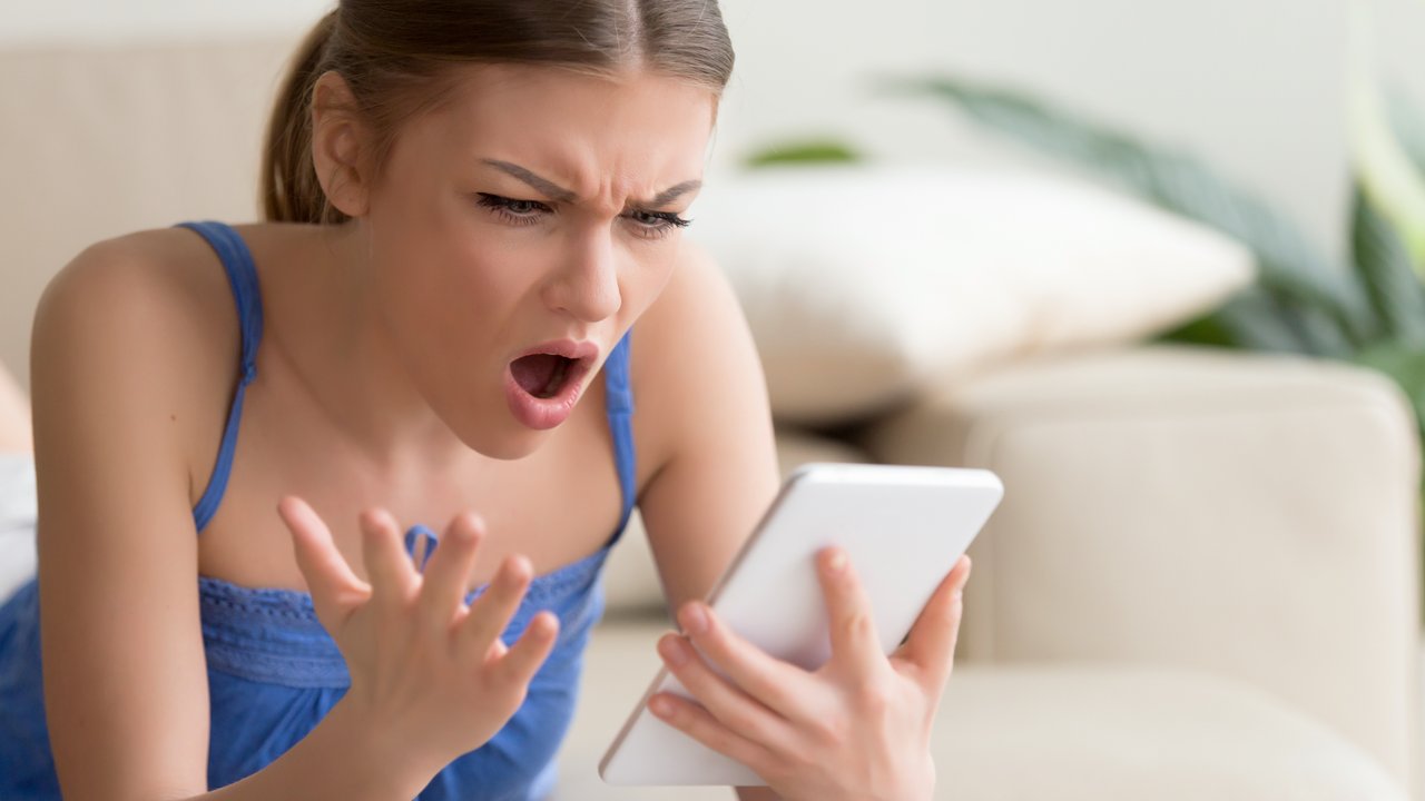 Young woman feeling shocked and looking with confusion on digital tablet screen while browsing online at home. Outrageous photos or disgusting content in social network, unbelievable news in Internet