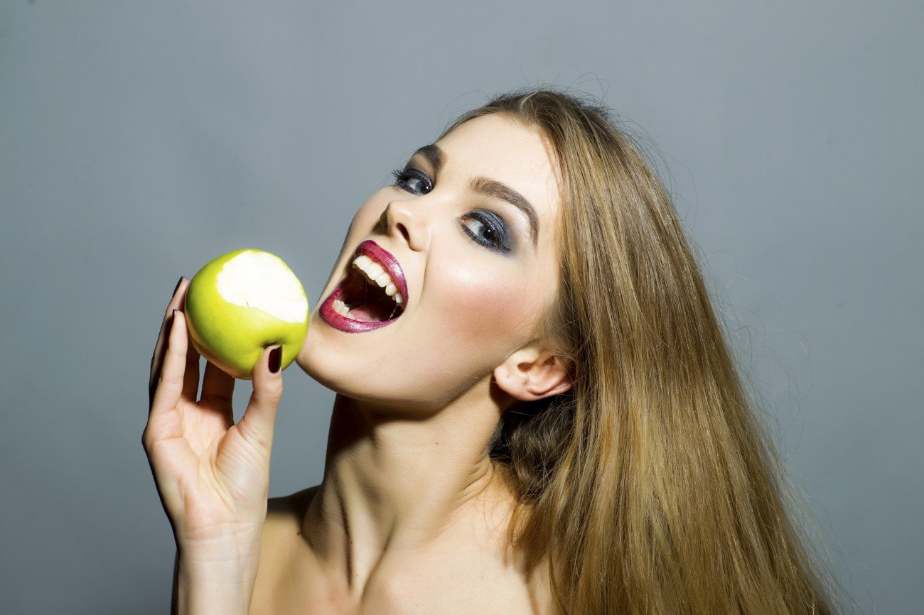 Eine Frau möchte in einen Apfel beißen