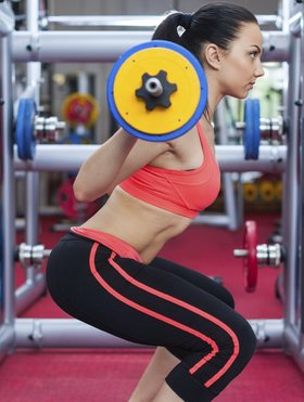 Woman in gym sport exercising squating with barbell lifting weights, young girl working out Woman in gym sport exercising squating with barbell lifting weights, young girl working out