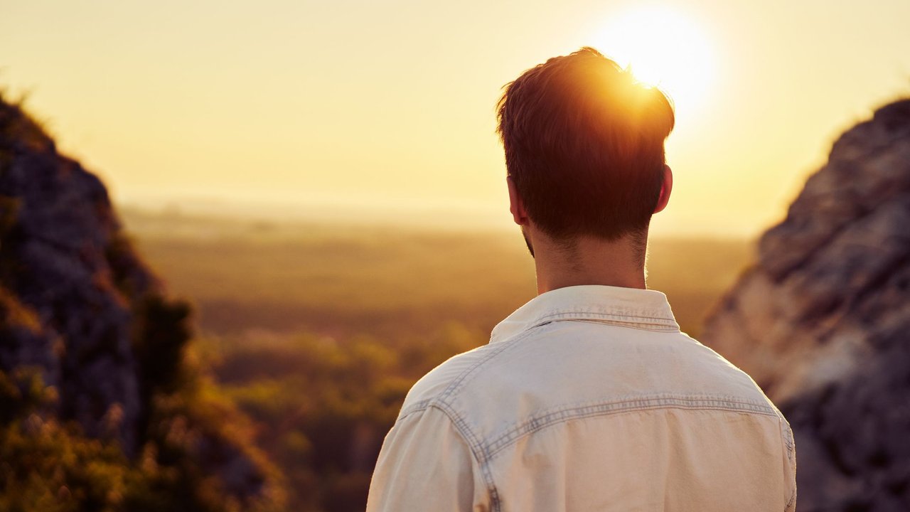 Back of a man watching sunset hiking in mountains