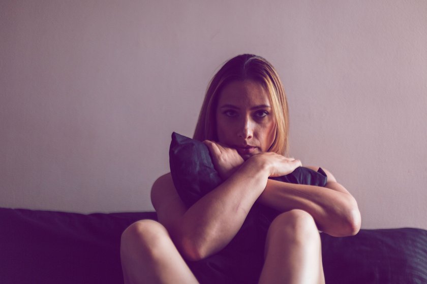 Frau mit traurigem Blick sitzt im Bett