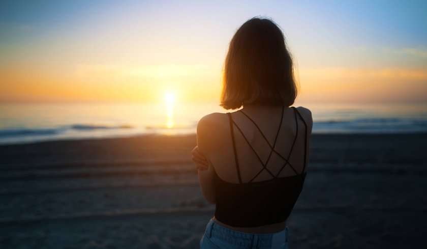 Jugendliches Mädchen am Meer bei Sonnenuntergang
