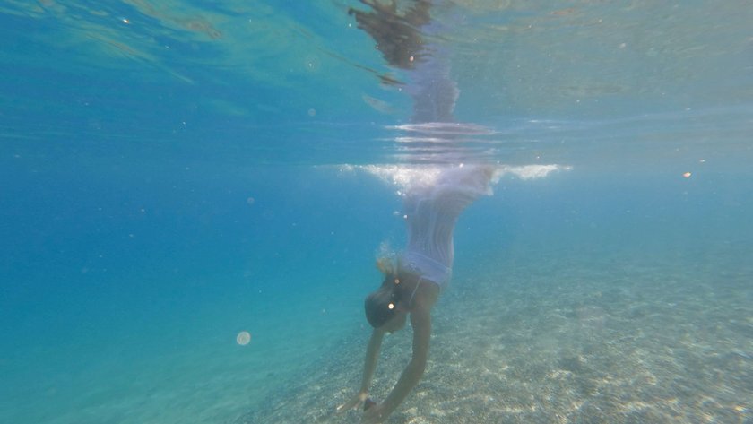 Eine Frau in einem weißen Kleid springt gerade ins Wasser