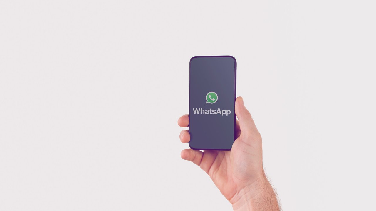 Hand holding smart phone with popular online text / call application "WhatsApp" logo on screen. Illustrative editorial image with copy space for text.