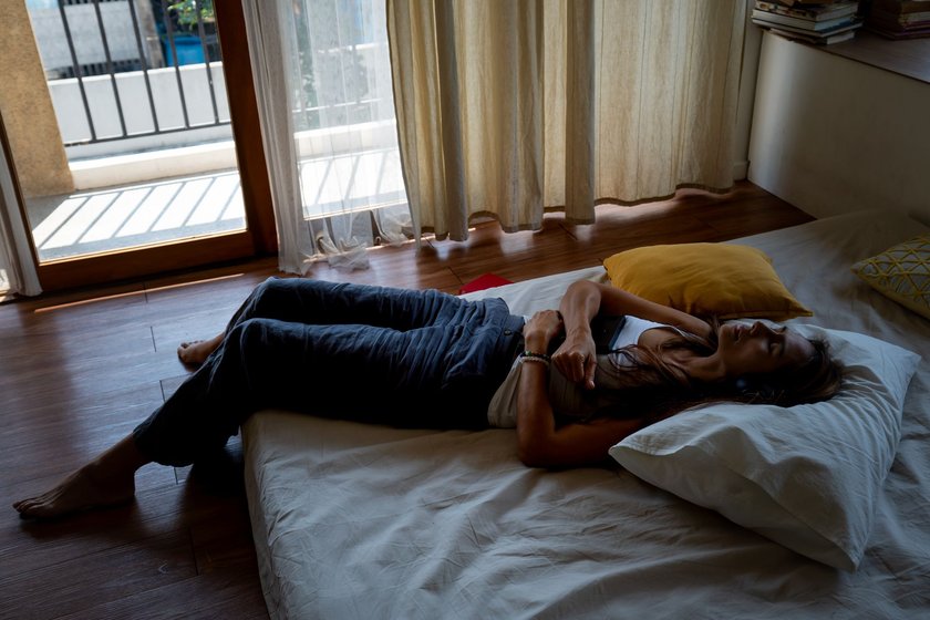 Depressed Asian mature woman lying on the bed by window with closed eyes and hopeless. Loneliness sad female being alone in bedroom with negative emotion. Mental health and life problem concept