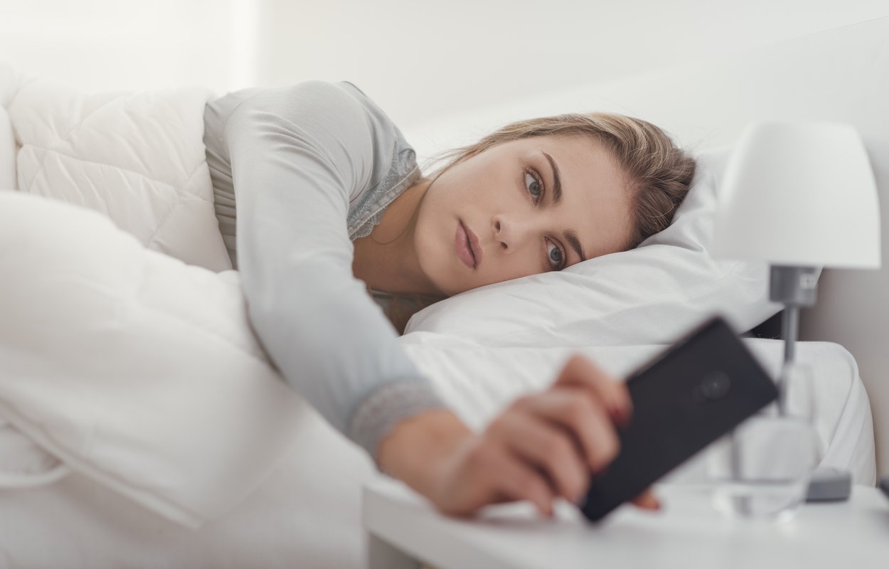 Frau wacht auf und schaut aufs Handy Frau wacht auf und schaut aufs Handy