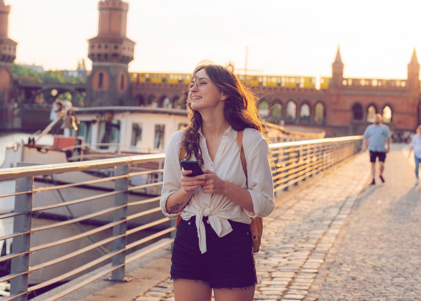 Frau läuft mit Smartphone durch Berlin