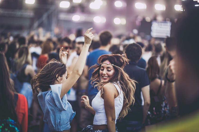 Zwei junge Frauen tanzen auf einem Musikfestival und sind glücklich