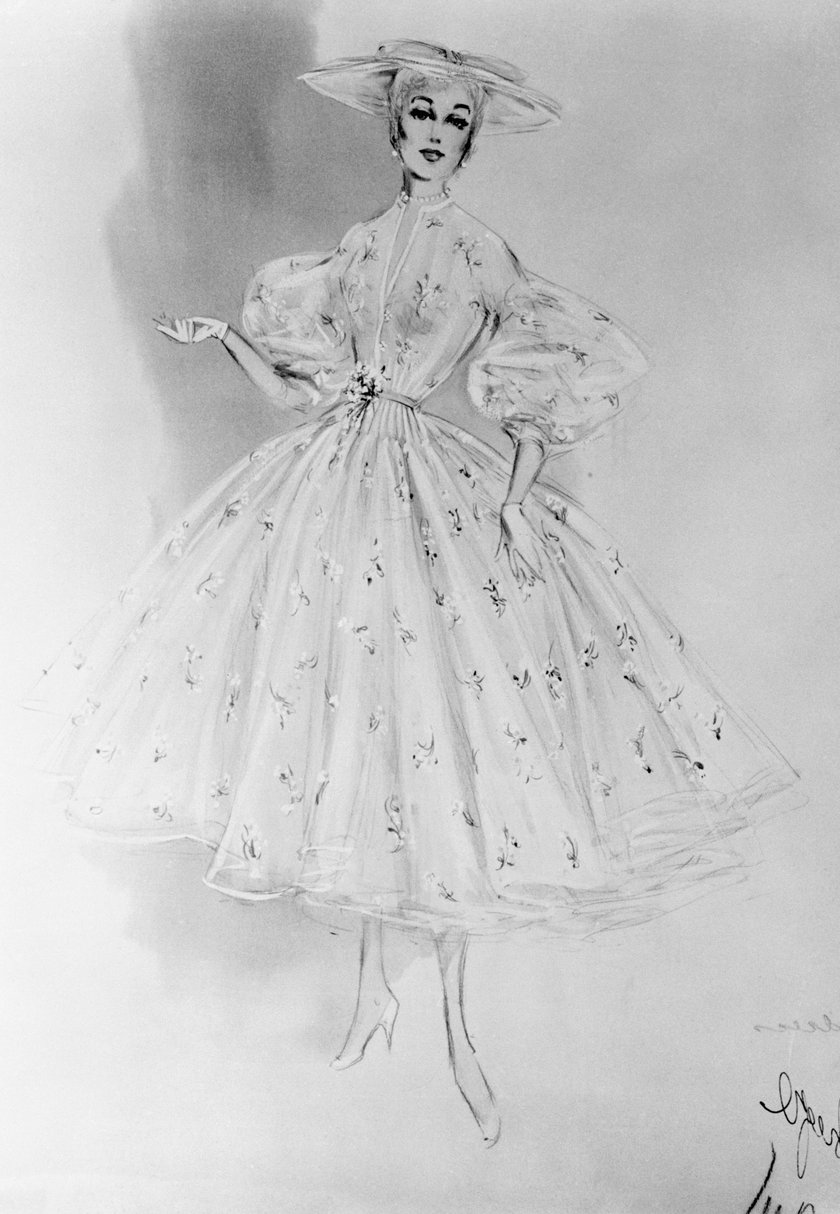 Diese elegante Skizze von Helen Rose zeigt das ikonische Organza-Kleid aus "Die Oberen Zehntausend" in seiner ganzen Pracht. Der weite Tellerrock, die dramatischen Puffärmel und das dazugehörige Organza-Hütchen wurden hier bis ins kleinste Detail festgehalten.Besonders raffiniert: Alle Kostüme aus dem Film waren ein Hochzeitsgeschenk von MGM an Grace Kelly. So wurde Mode zur persönlichen Ausstattung einer echten Prinzessin - ein einmaliges Geschenk der Filmstudios an ihren größten Star.
