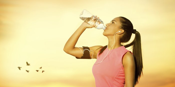 Eine Joggerin trinkt im Sonnenuntergang Wasser Eine Joggerin trinkt im Sonnenuntergang Wasser