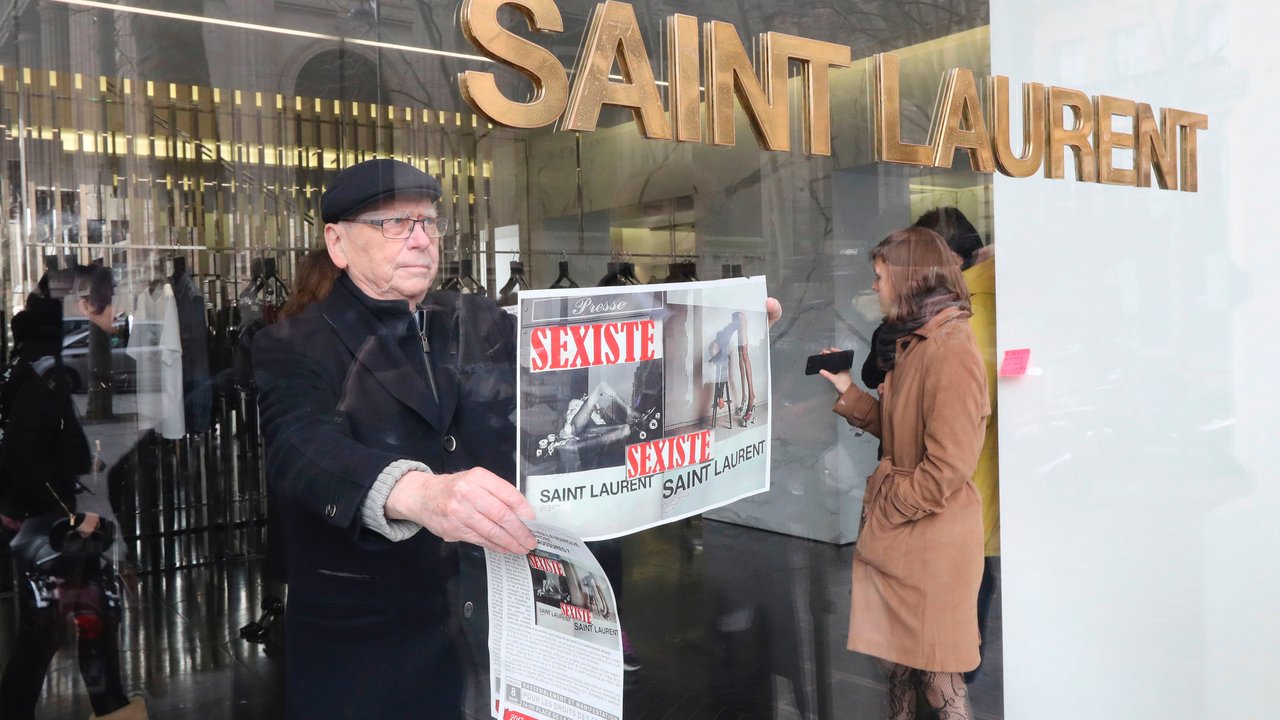 An activist of Effronte-e-s feminist movement puts a placard reading "sexist" in a Yves Saint-Laurent shop in Paris on March 7, 2017 during a demonstration against a new publicity campaign of the French luxury fashion brand.                               
A new publicity campaign featuring painfully thin models in "degrading" poses for the French fashion house Yves Saint Laurent sparked outrage March 6, with calls for it to be banned. The poster campaign across Paris of a reclining woman in a fur coat and fishnet tights opening her legs, and another of a model in a leotard and roller skate stilettos bending over a stool, caused fury on social media. / AFP PHOTO / Jacques DEMARTHON        (Photo credit should read JACQUES DEMARTHON/AFP/Getty Images)