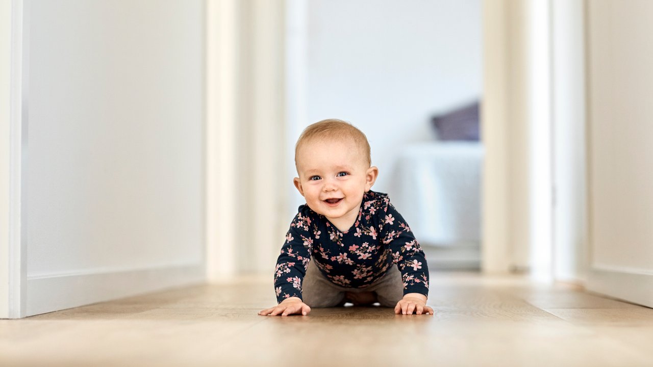 Portrait of cute baby boy crawling in corridor. Smiling male toddler is wearing casuals. He is at home.