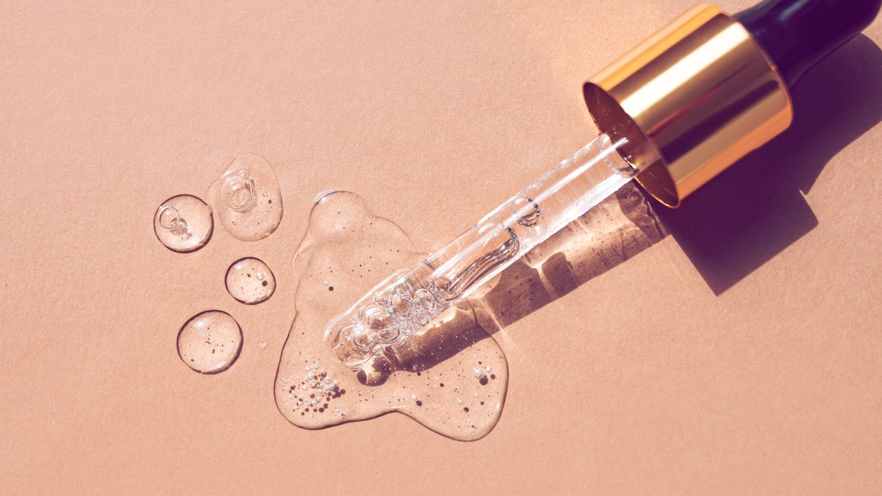 Serum drops and a pipette on a beige background. Top view.