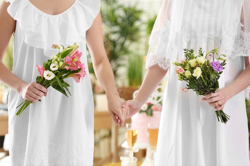 Zwei Frauen halten Händchen auf ihrer Hochzeit