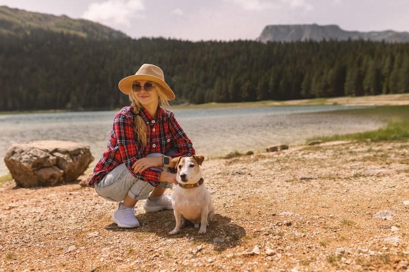A cute young girl traveler holds her Jack Russell terrier puppy in nature. Animals best friend, beautiful friendship.