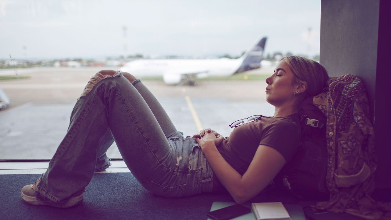 Frau macht am Flughafen ein Nickerchen