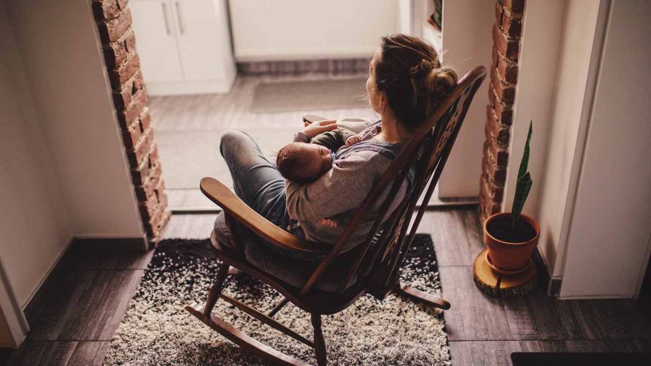 Photo of a young mother holding her newborn baby, while sitting in a rocking chair