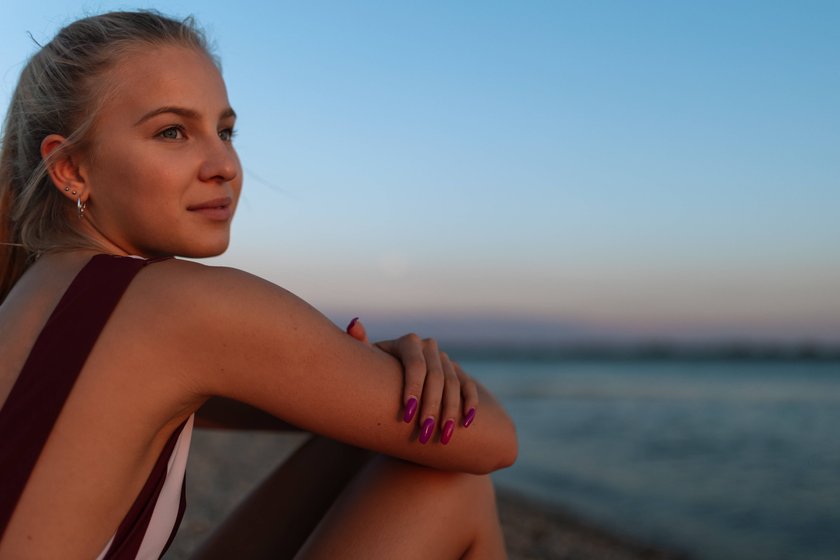 Junge Frau sitzt alleine am Strand