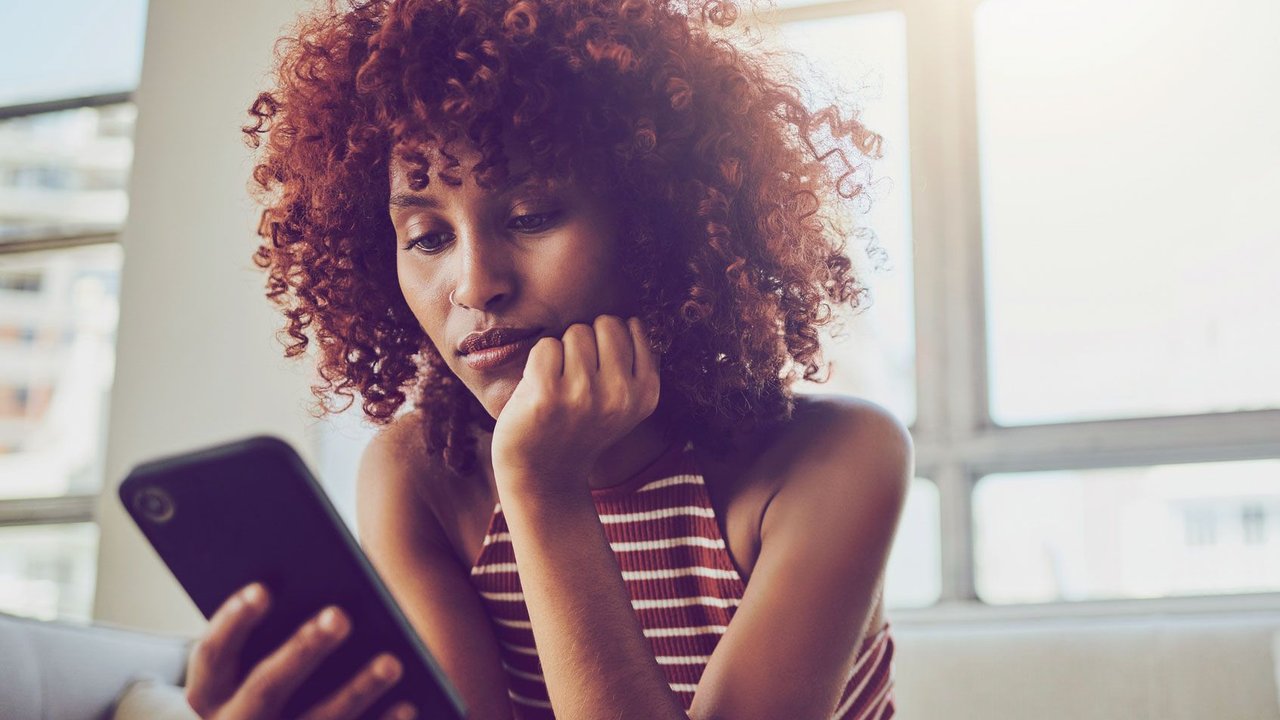 Frau, die genervt aufs Smartphone schaut