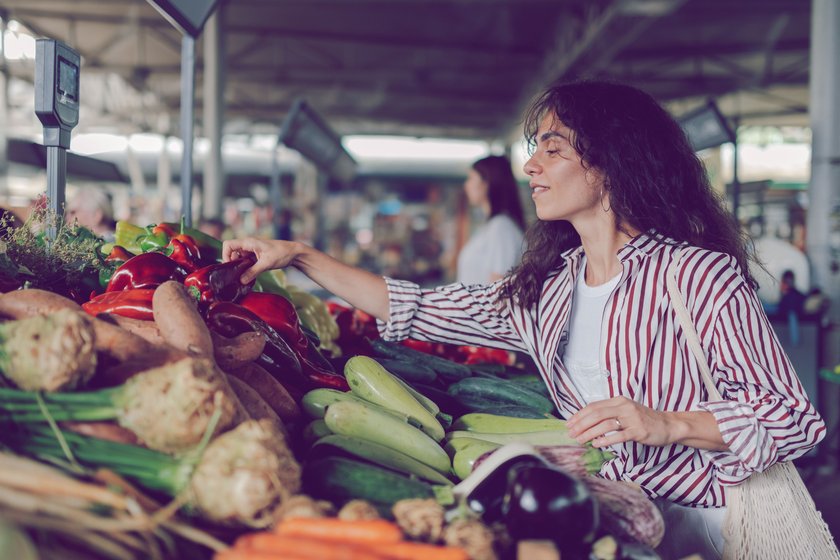 Frau kauft Gemüse auf einem Markt