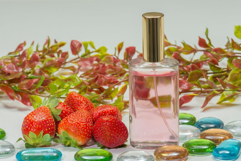 A spray bottle of fragrance  strawberries and red and ripe strawberries