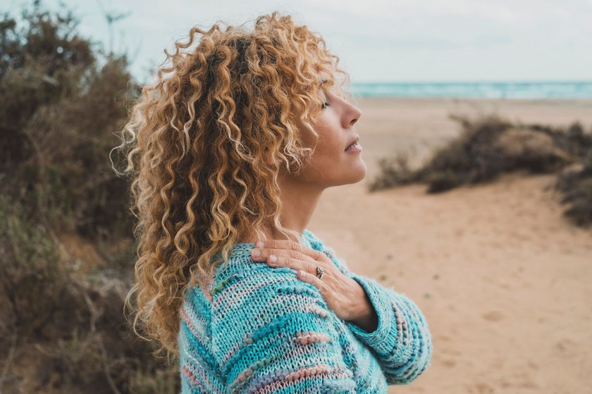 Eine Frau ist am Strand, genießt die Ruhe und denkt nach
