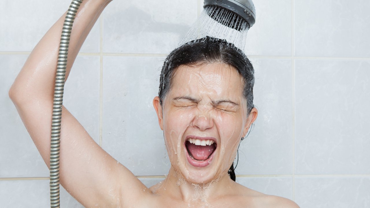 Portrait of a young woman in bathroom screaming in shower