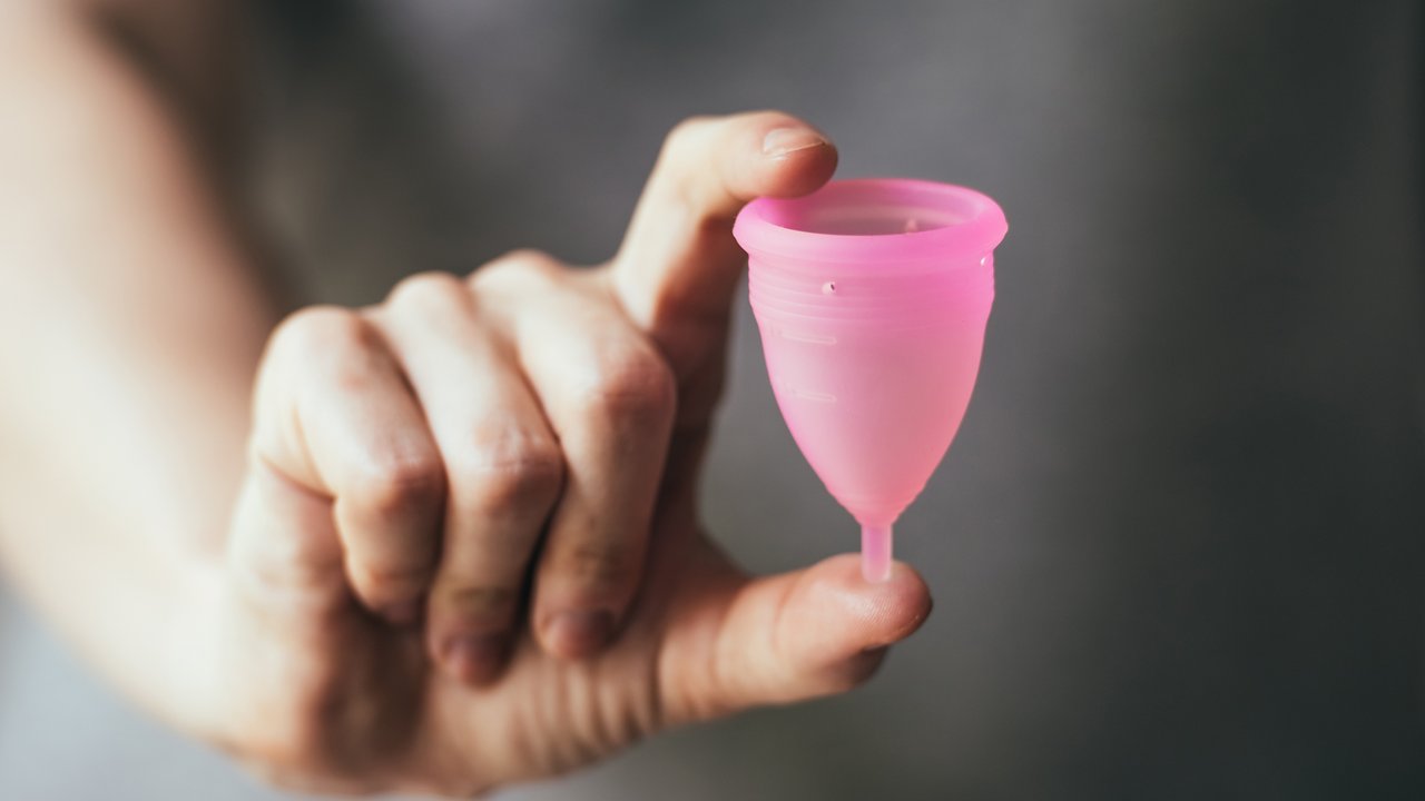 Young woman hand holding menstrual cup. Selective focus and shallow DOF