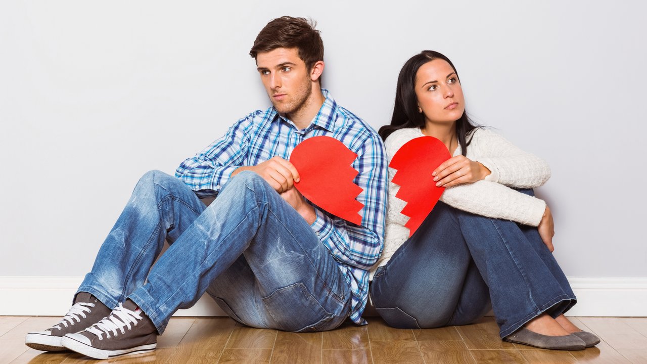 Young couple sitting on floor with broken heart at home