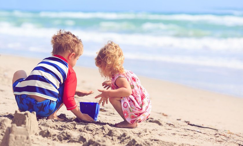 zwei Kinder spielen am Meer im Sand